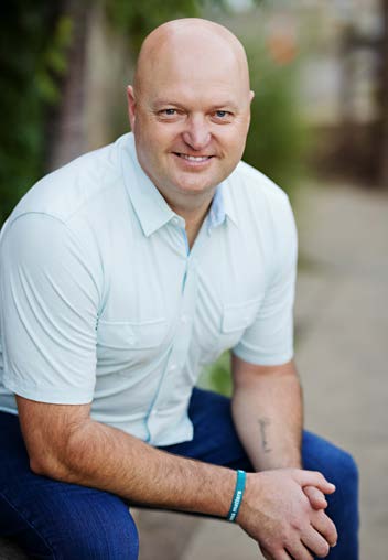 Arik Housley, seated outdoors, smiling